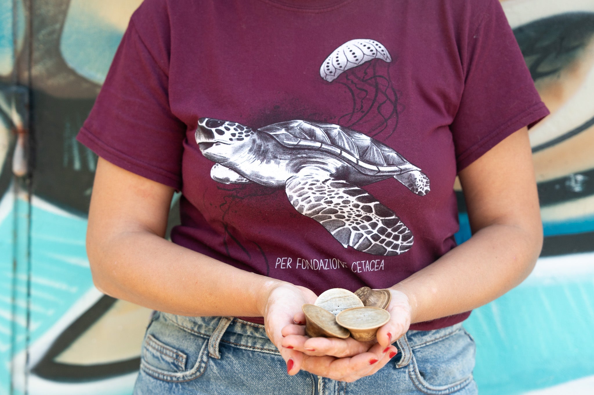 T-shirt Per Fondazione Cetacea e capsule Nipple in fibra vegetale tenute nel palmo delle mani